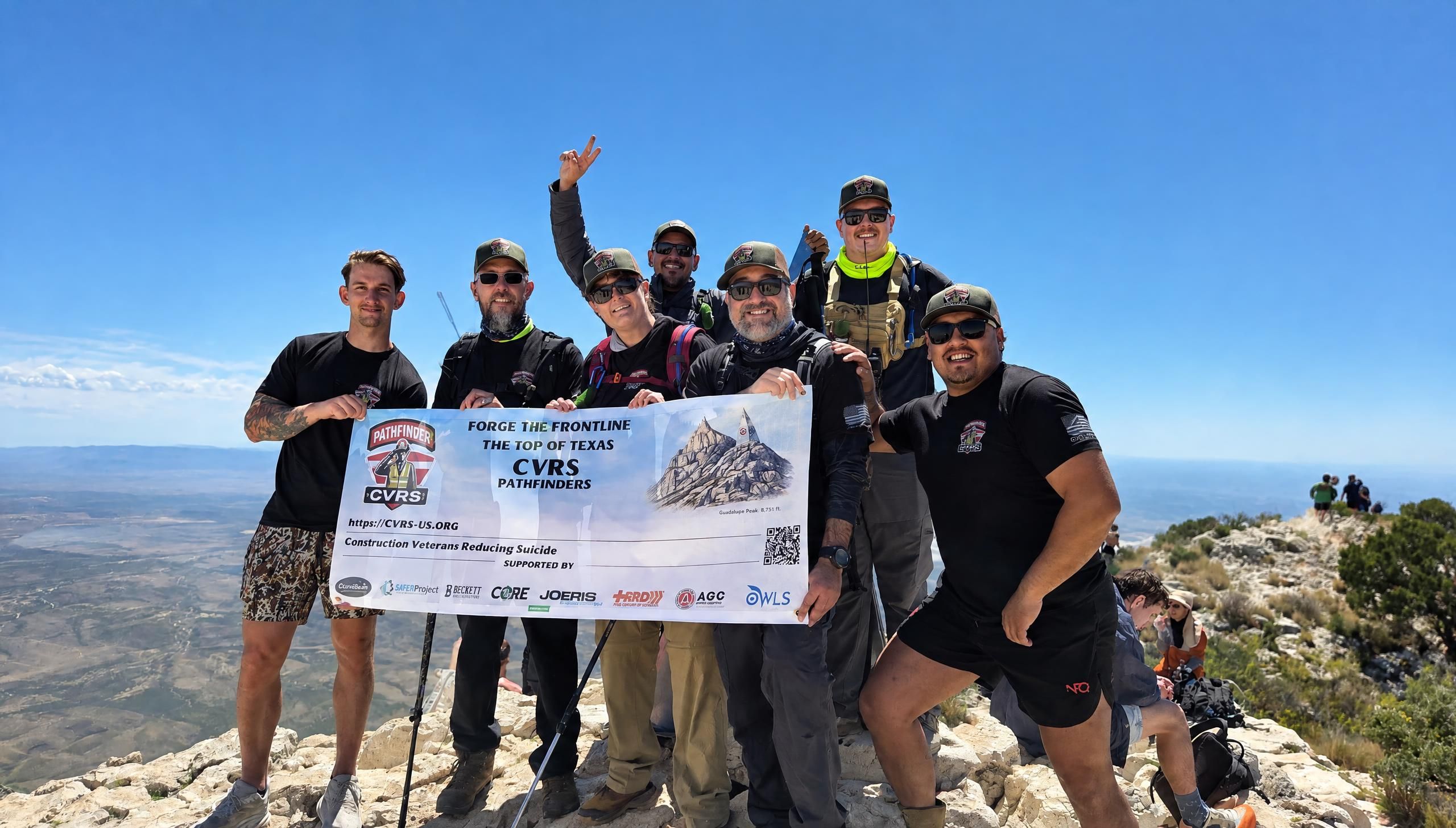 hikers holding banner on top of Gualupe Peak